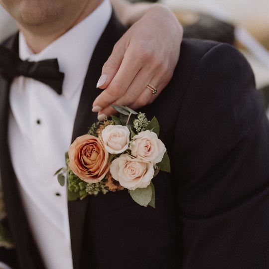Man in a tuxedo with a floral boutonniere on a blurred background