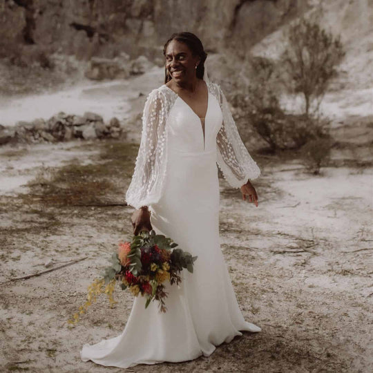 Woman in a white wedding dress holding a bouquet in a beach setting